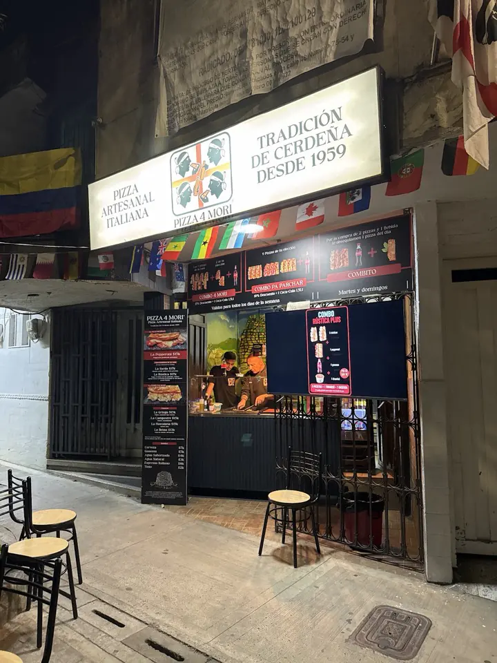 Fachada de Pizza 4 Mori con su aviso, banderas y bancos