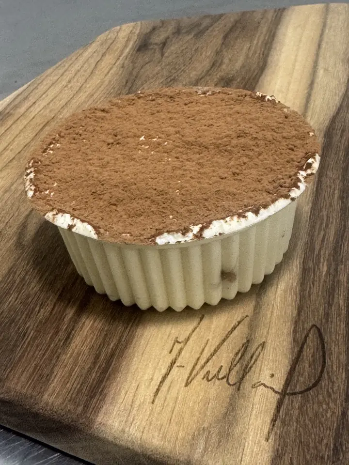 Tiramisú en recipiente individual, espolvoreado con cacao